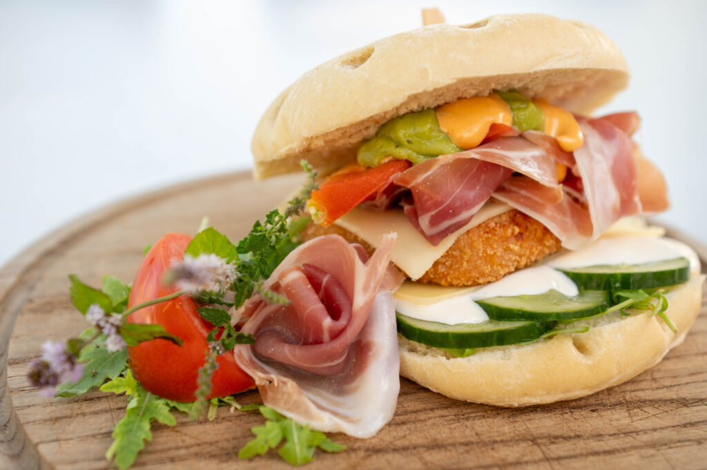 Mac&Chees Burger American vs Italia / Fladenbrot-Burger mit Salat, Sauercreme, Maccaroni-Cheddarkäse-Paddy, Parmaschinken, Tomate, Gurke und Cocktailsauce